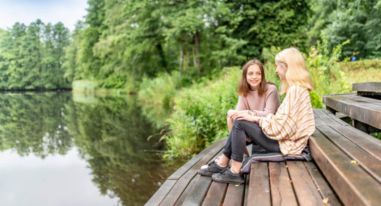 Mädchen sitzen auf einem Steg am See