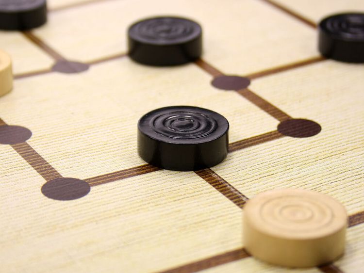 schwarze und weiße Mühlesteine auf einem Spielbrett