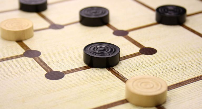 schwarze und weiße Mühlesteine auf einem Spielbrett