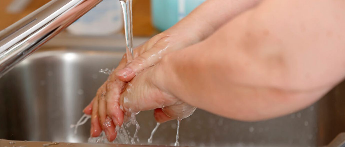 Handwaschen unter Wasserhahn im Waschbecken