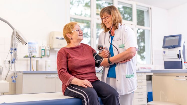 Pflegekraft misst Blutdruck bei einer älteren Patientin