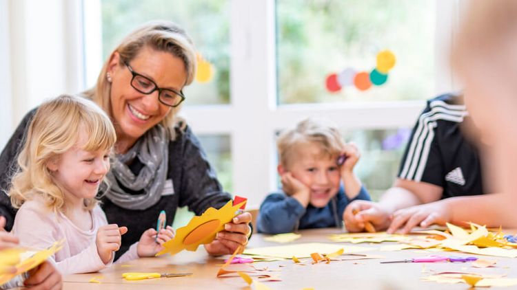 Kinder mit Pädagogin beim Basteln
