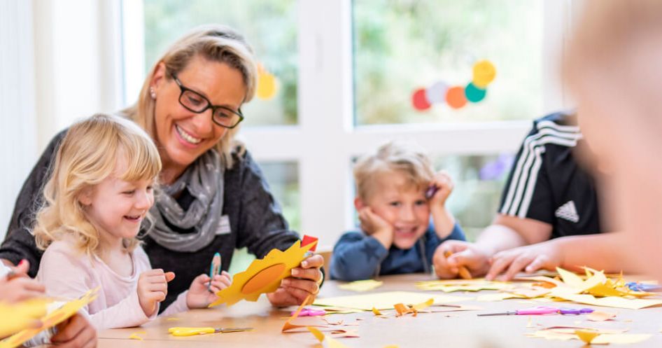 Kinder mit Pädagogin beim Basteln
