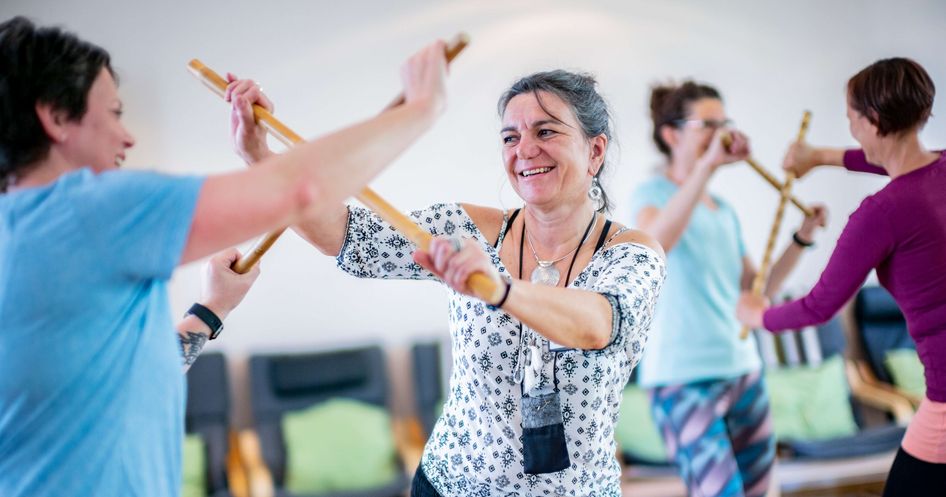 Patienten trainieren mit Stöcken in der Bewegungstherapie