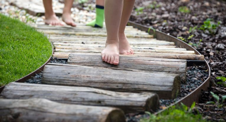 Kinder spazieren auf einem Barfußpfad