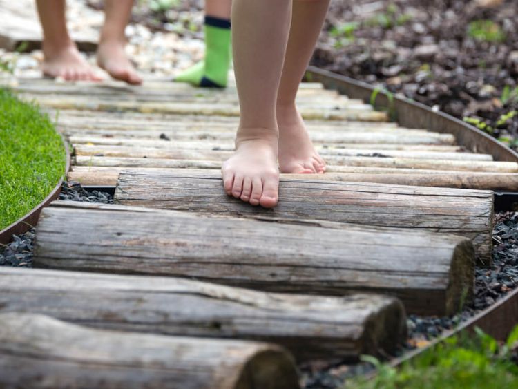 Kinder spazieren auf einem Barfußpfad