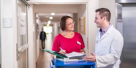 Arzt und Pflegekraft besprechen Patientenakten bei der Übergabe