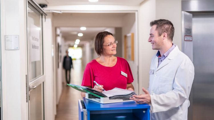 Arzt und Pflegekraft besprechen Patientenakten bei der Übergabe