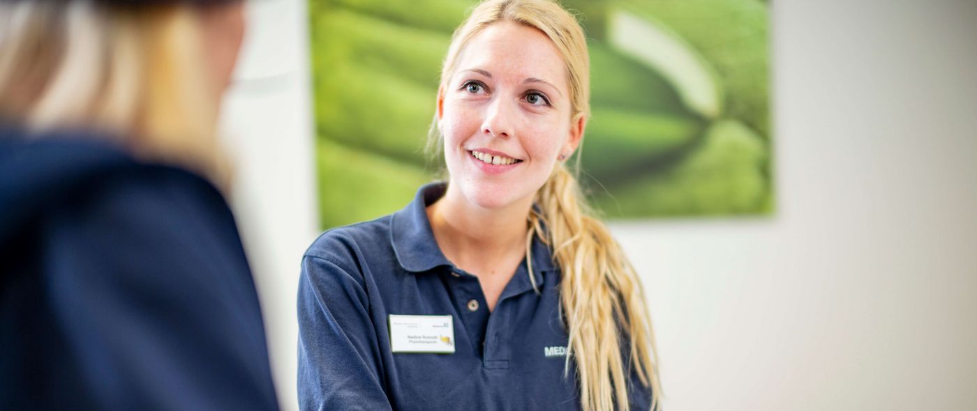 Eine Mitarbeiterin hilft einer Patientin beim Ausfüllen von Formularen