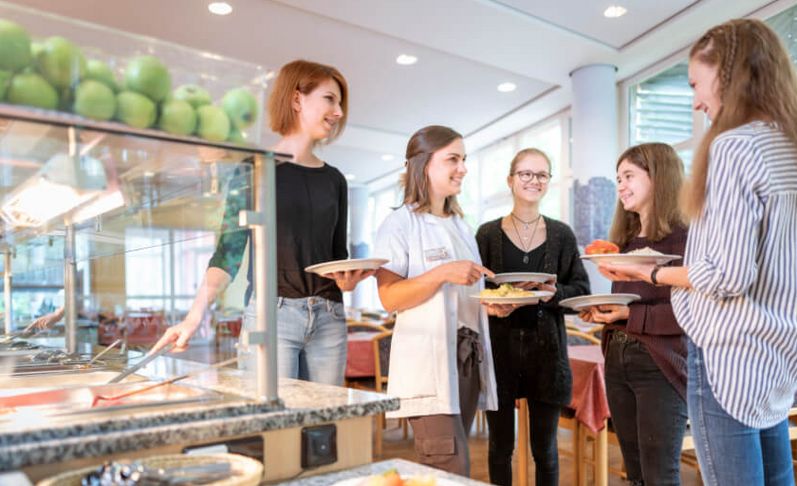 Gruppe Frauen in eine Cafeteria mit Essen in der Hand