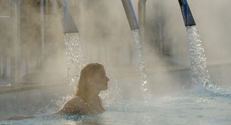 Junge Frau entspannt sich im Außenbecken eines Thermalbades