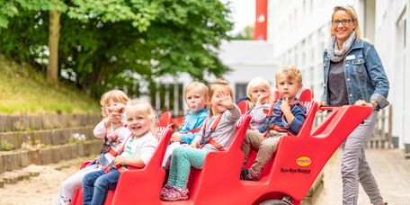 Kinder auf dem Klinikgelände auf dem Buggy Kinder auf dem Klinikgelände fahren in einem Krippenwagen