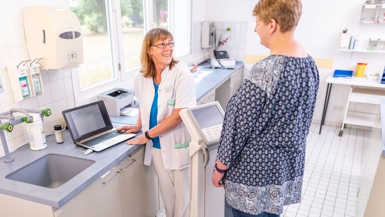 Pflegekraft wiegt einen Patienten auf der Waage