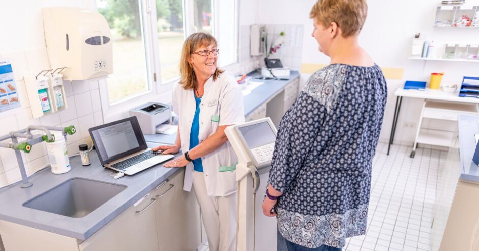 Pflegekraft wiegt einen Patienten auf der Waage