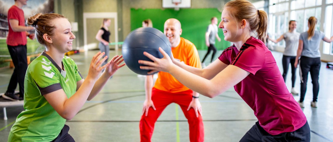 Junge Patienten werfen sich in der Sporttherapie einen Ball zu