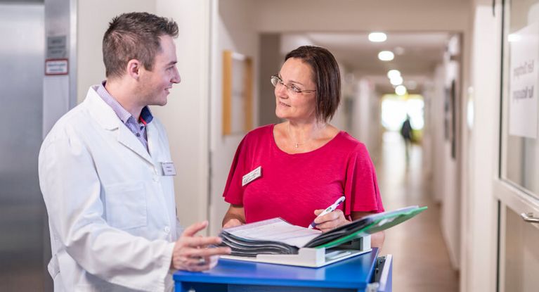 Arzt und Pflegekraft besprechen Patientenakte bei der Übergabe