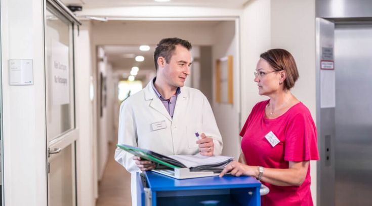 Arzt und weibliche Pflegekraft studieren gemeinsam eine Patientenakte